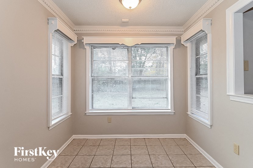 a living room with three windows and a tiled floor