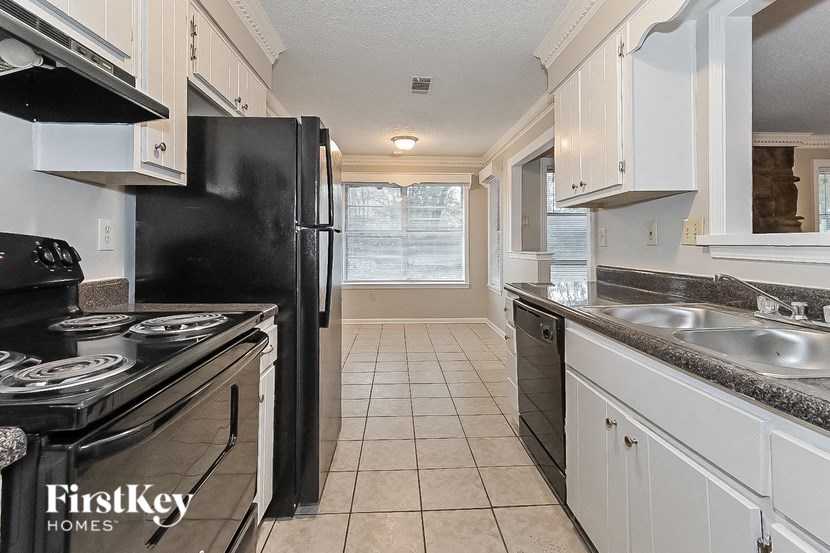 a white kitchen with black appliances and white cabinets