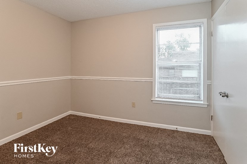 the bedroom of a house with a carpeted floor and a window