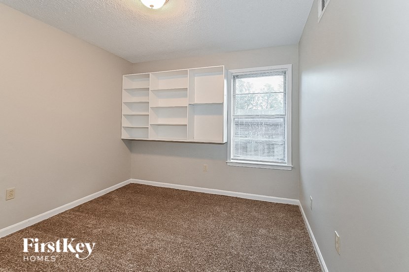 a bedroom with white shelves and a window