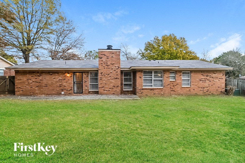 a brick house with a grassy yard and a fence