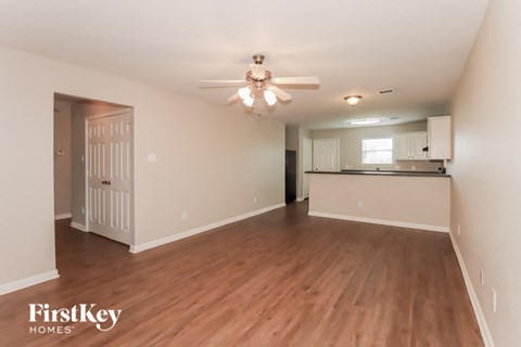 A spacious room with wooden floors and a ceiling fan.