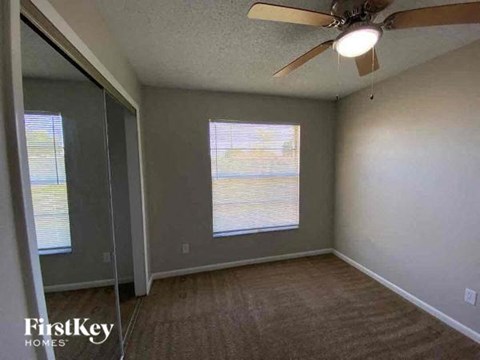 A room with a ceiling fan and a window with blinds.