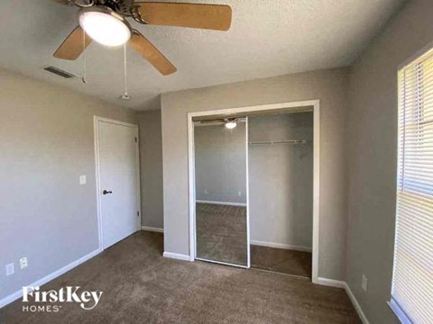 A room with a ceiling fan and a sliding glass door leading to a balcony.