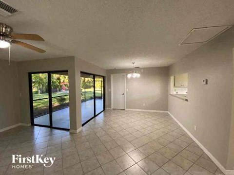 A spacious room with a ceiling fan and sliding glass doors leading to a garden.