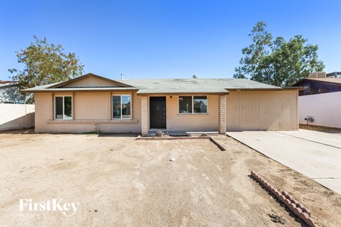 a small brown house with a dirt lot and a driveway