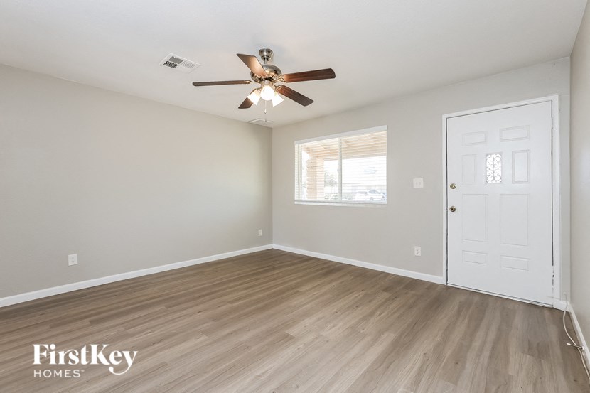 an empty bedroom with a ceiling fan and a door