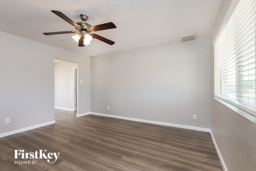an empty living room with a ceiling fan and a window