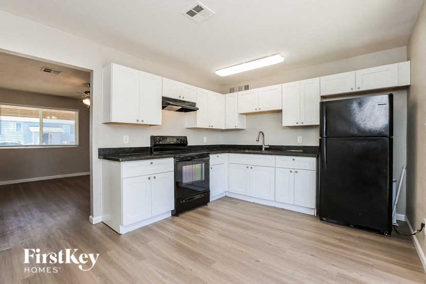 an empty kitchen with white cabinets and black appliances