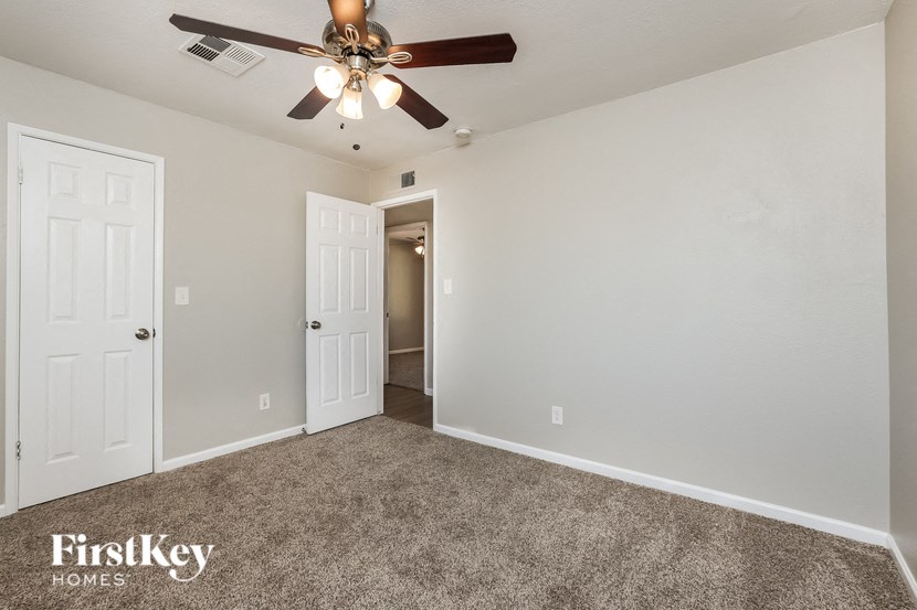 a bedroom with a ceiling fan and a door to a hallway