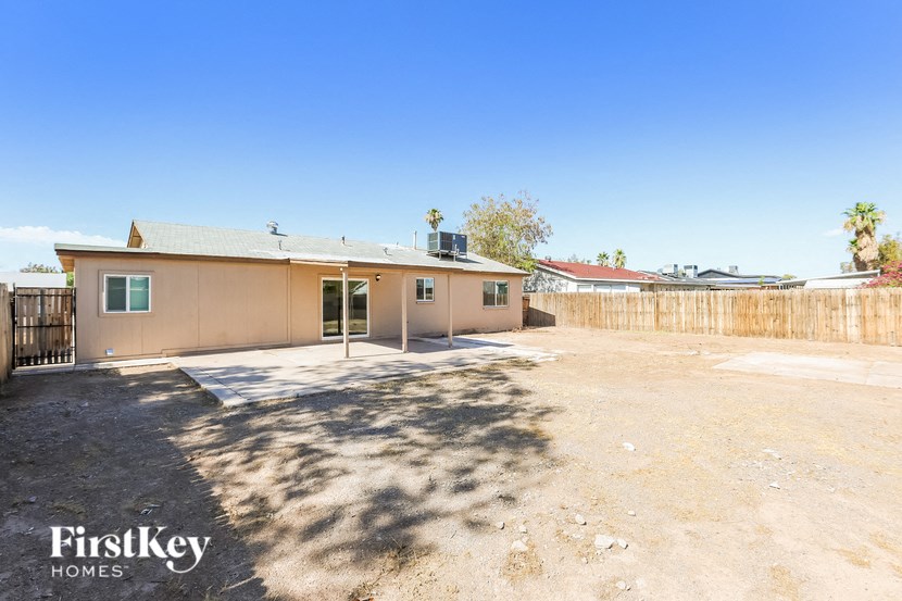 a house with a dirt lot and a fence