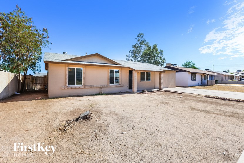 a home in a dirt lot with a house and a dirt driveway