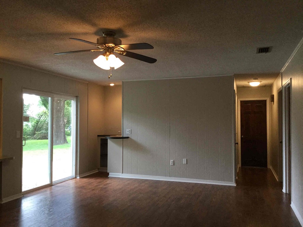 an empty living room with a ceiling fan