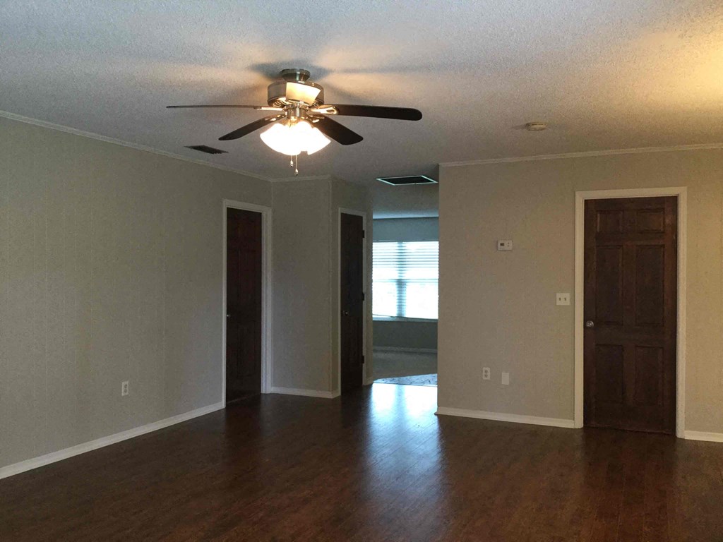 an empty living room with a ceiling fan