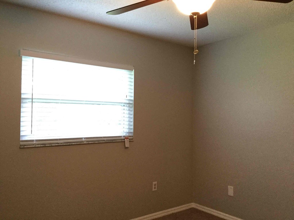 a bedroom with a ceiling fan and a window