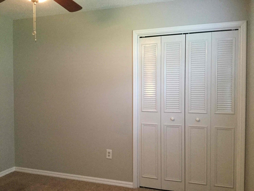 a bedroom with three closets and a ceiling fan