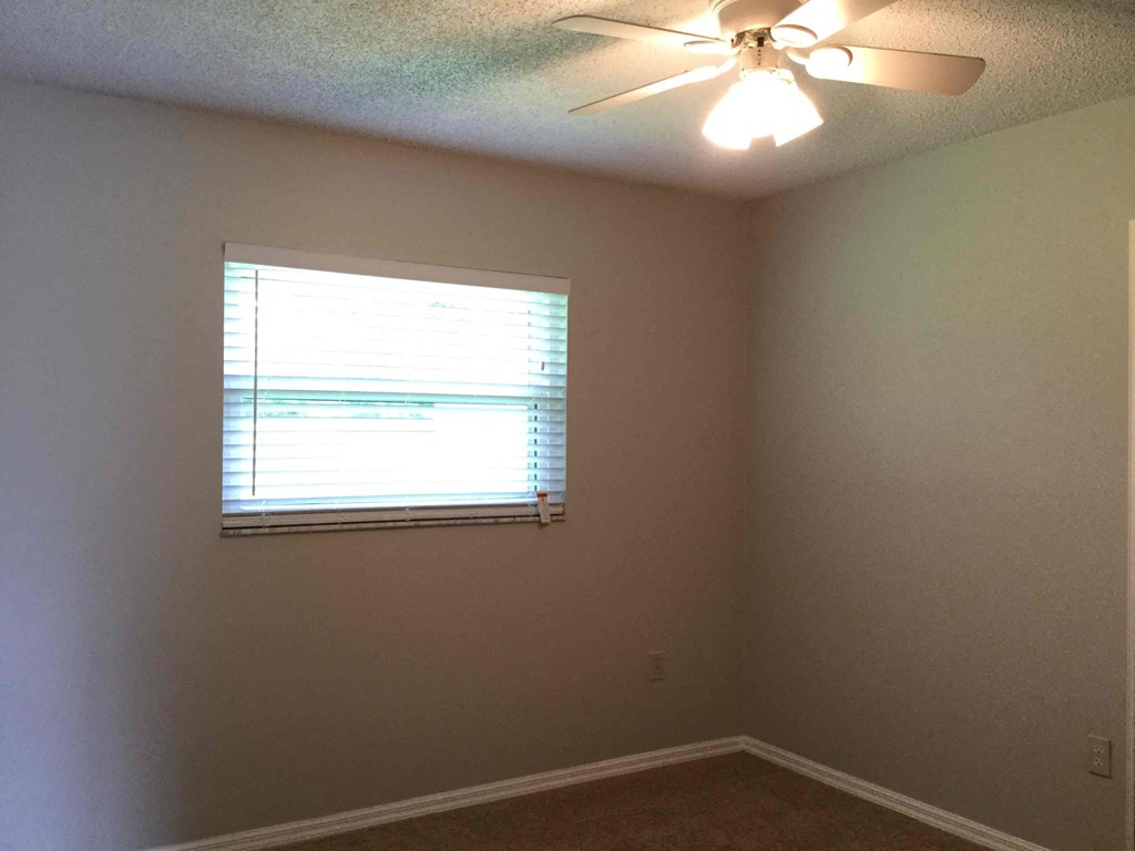 a living room with a window and a ceiling fan