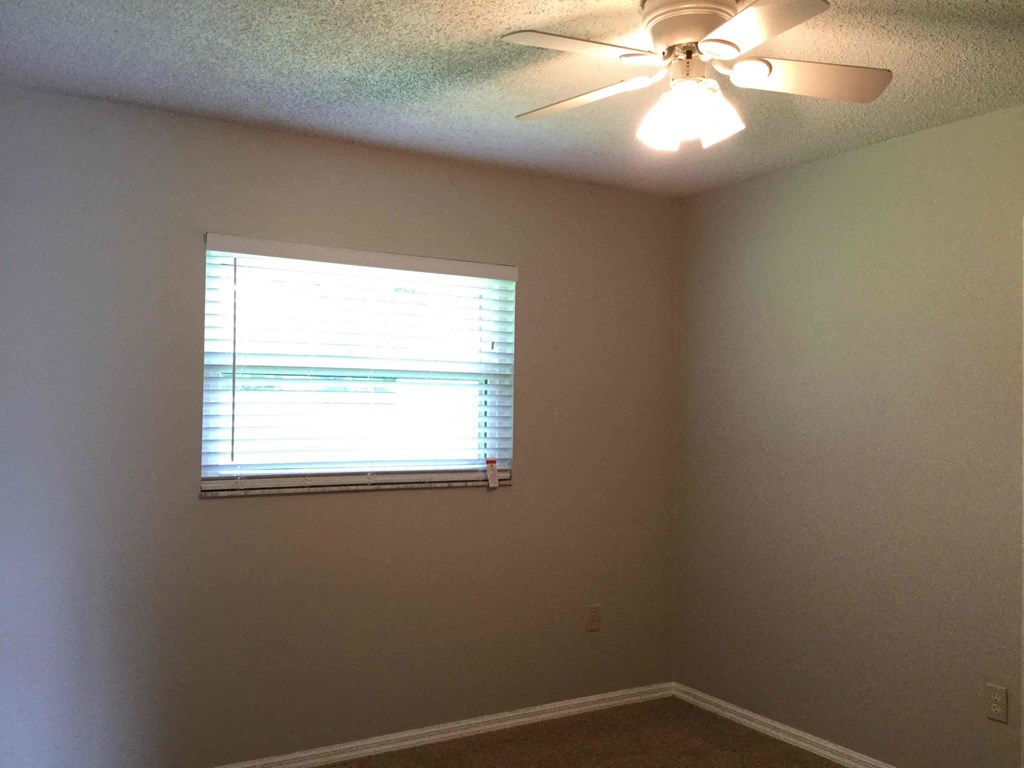 a living room with a window and a ceiling fan