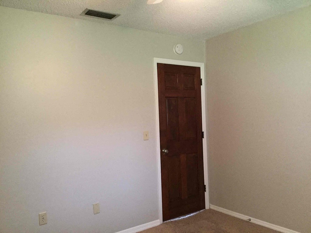 a room with white walls and a wooden door     and a white