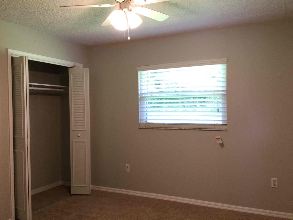 a room with a window and a closet and a ceiling fan