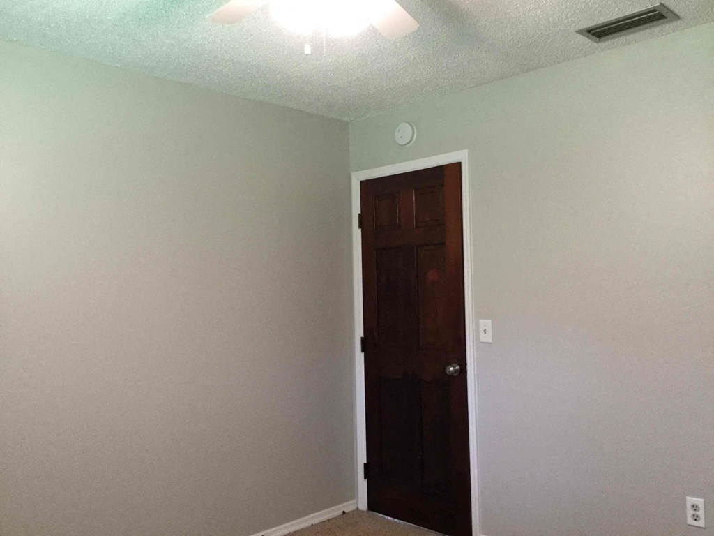 a room with a white wall and a brown door