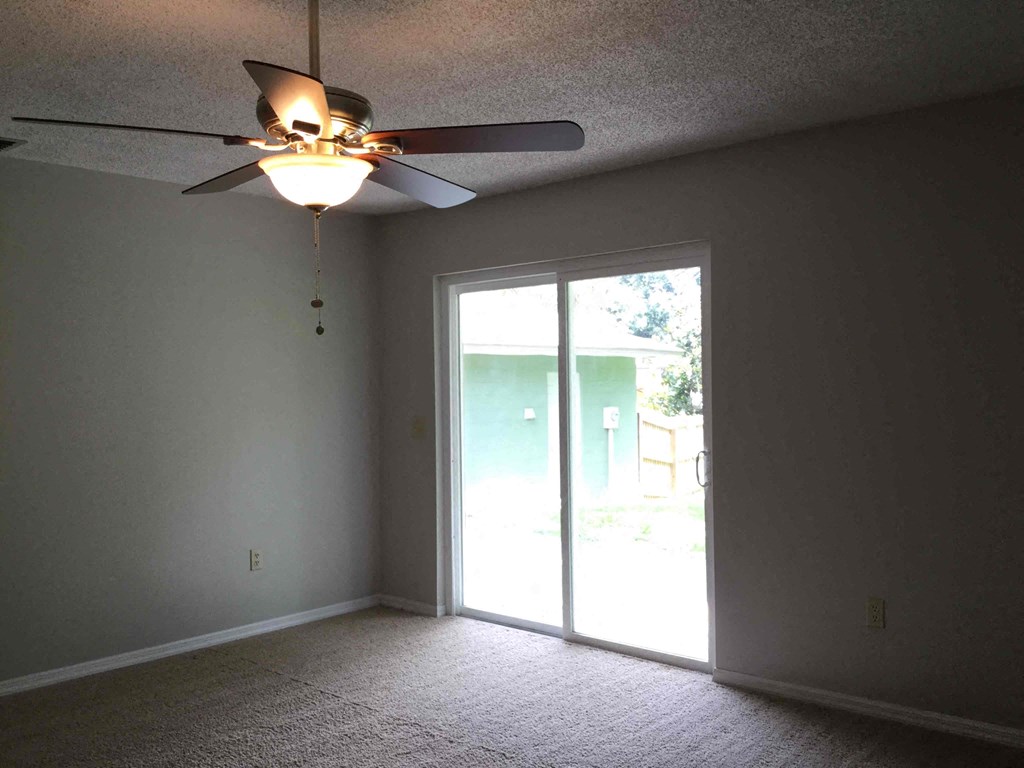 a living room with a ceiling fan and a sliding glass door