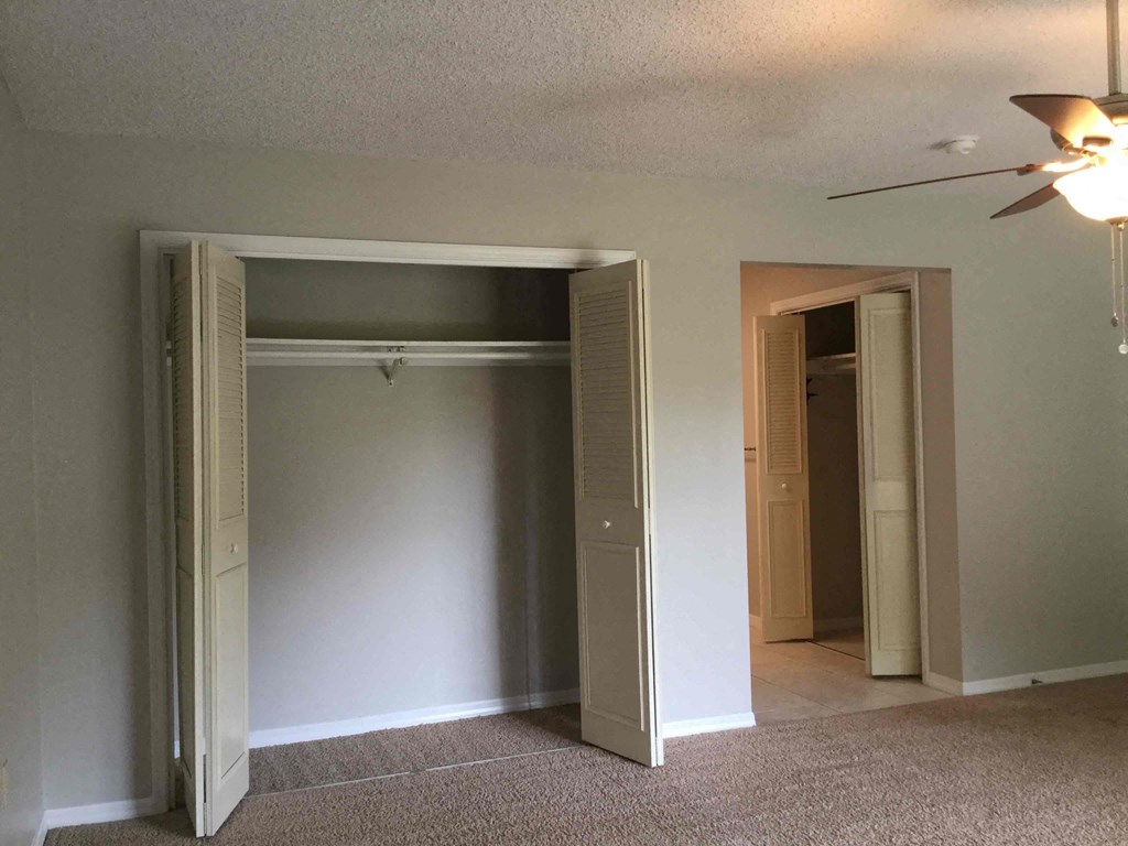 an empty living room with a ceiling fan and open doors