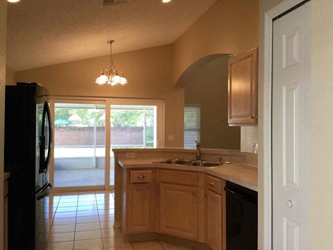 A kitchen with a black fridge and wooden cabinets.