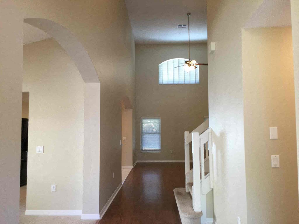 A hallway with a light on the ceiling and a window with blinds.