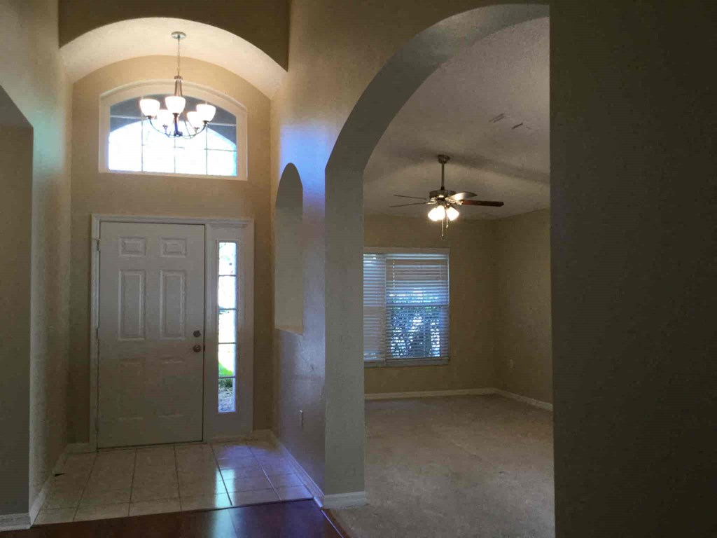 A room with a white door and a chandelier hanging from the ceiling.