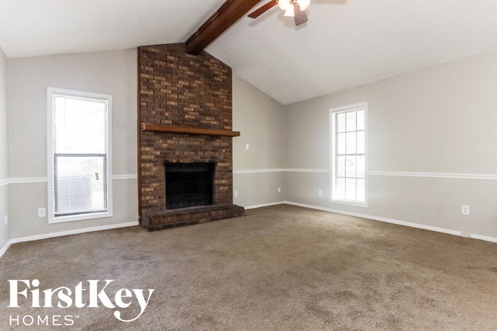 A room with a fireplace and two windows.