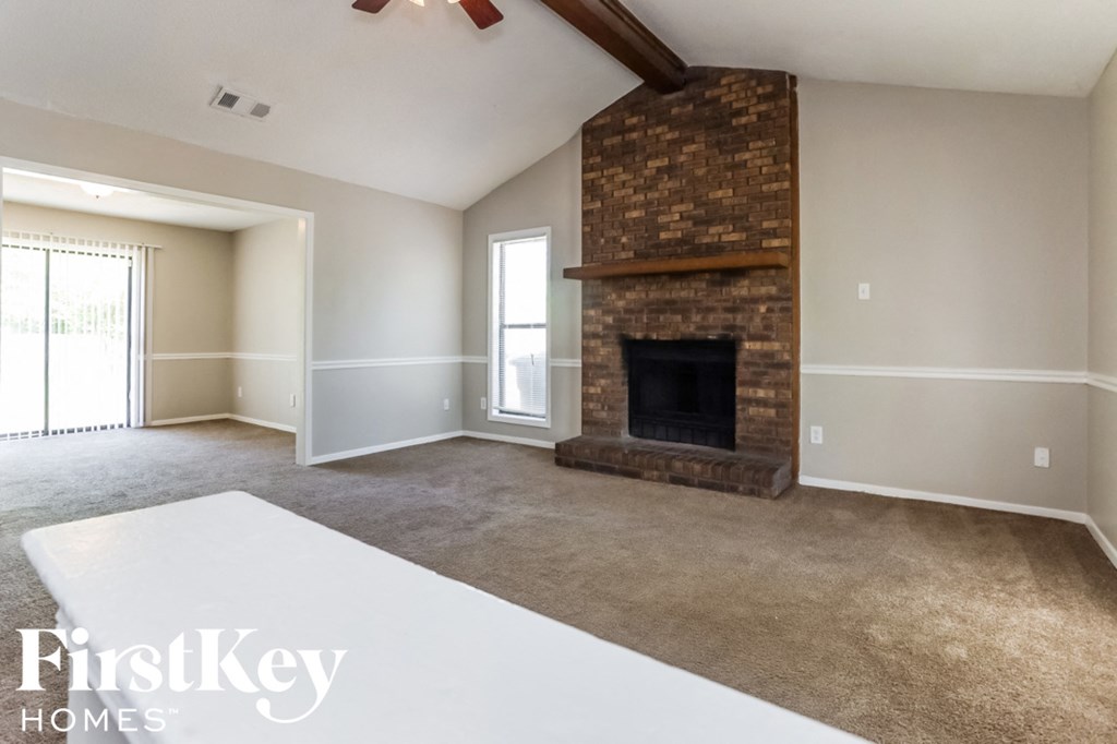 A spacious living room with a fireplace and a carpeted floor.