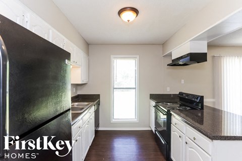 A kitchen with black appliances and white cabinets.