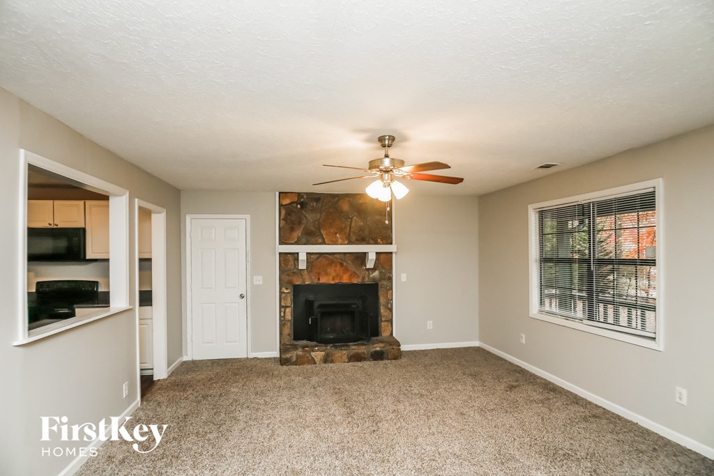 A living room with a fireplace and a ceiling fan.