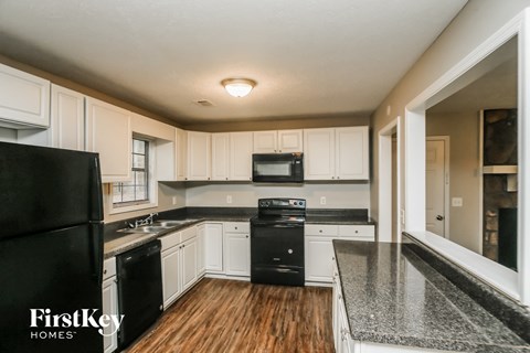 A kitchen with black appliances and wooden floors.
