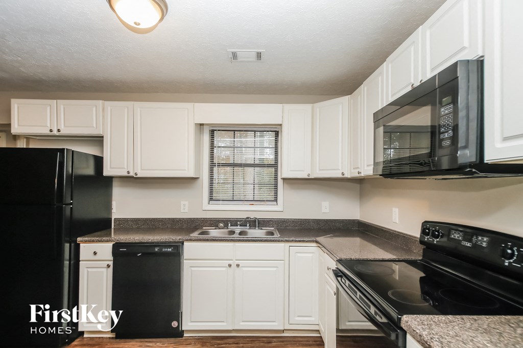 A kitchen with black appliances and white cabinets.