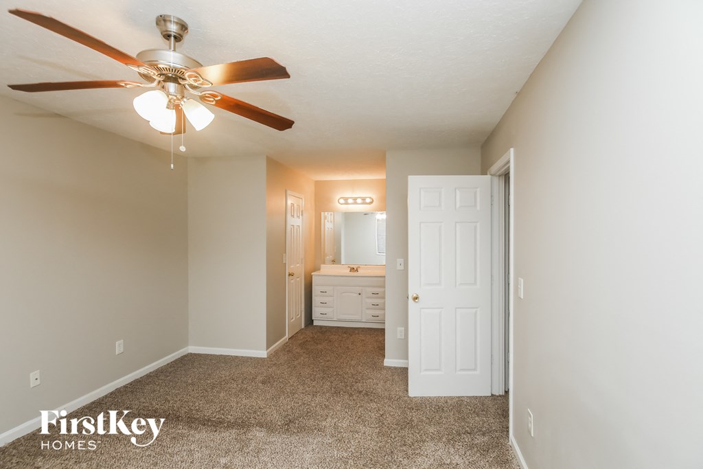A bedroom with a ceiling fan and a white door.