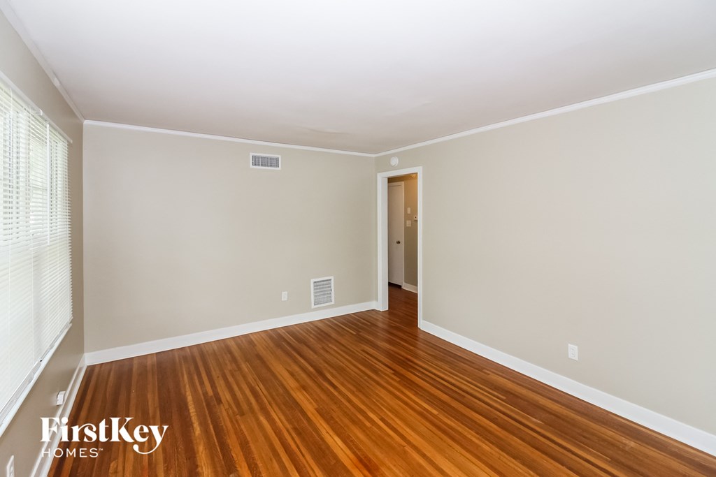 A room with wooden flooring and a door leading to another room.