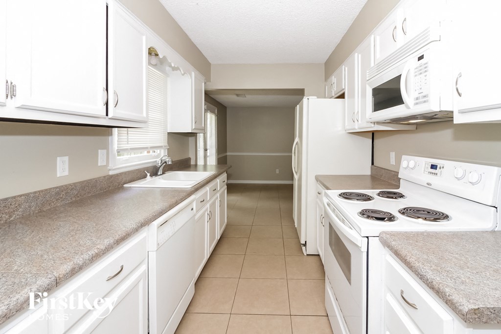 A kitchen with white appliances and cabinets.