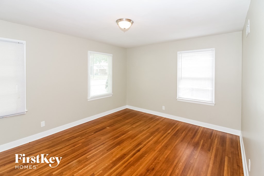 A room with wooden floors and two windows.
