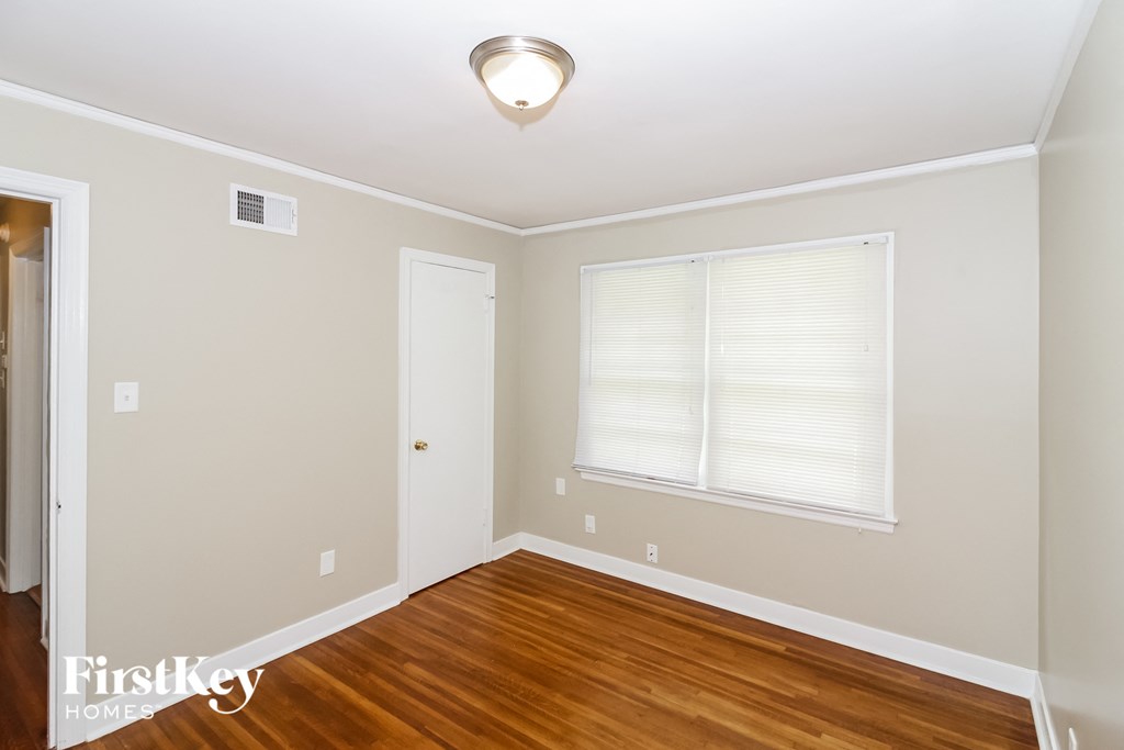 A room with a wooden floor and a window with blinds.