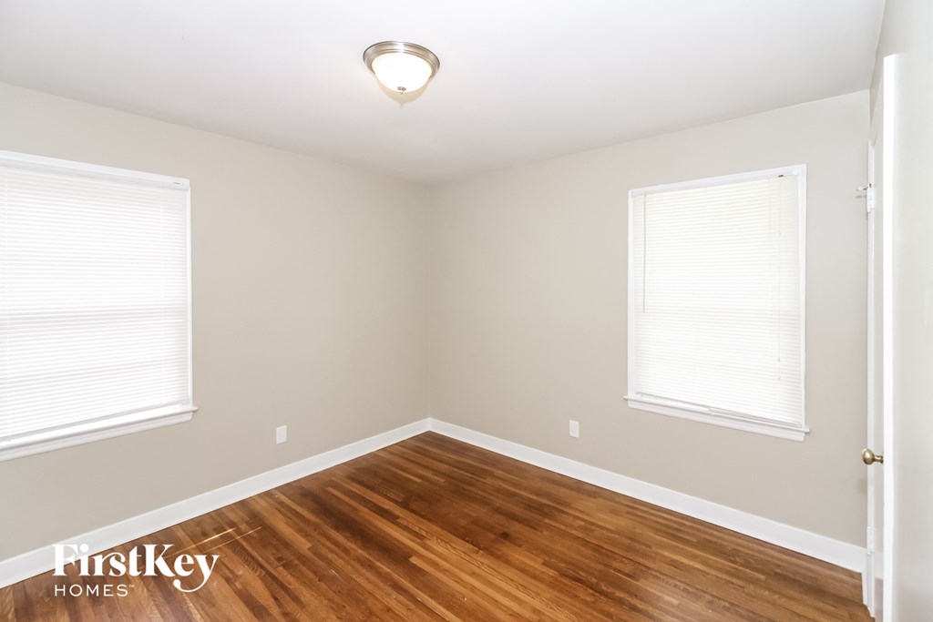 A room with wooden floors and a window with blinds.