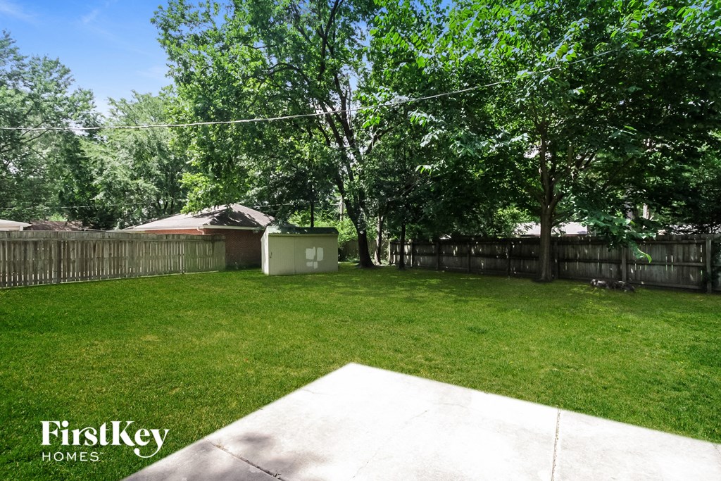 A backyard with a concrete slab and a fence.