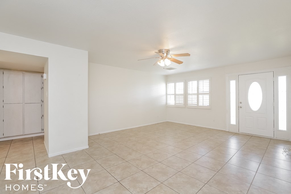 an empty living room with white walls and a ceiling fan