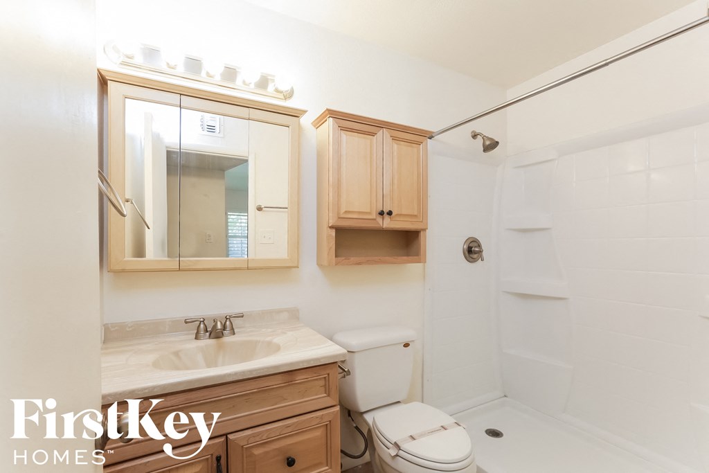 a bathroom with a toilet sink and mirror and a shower