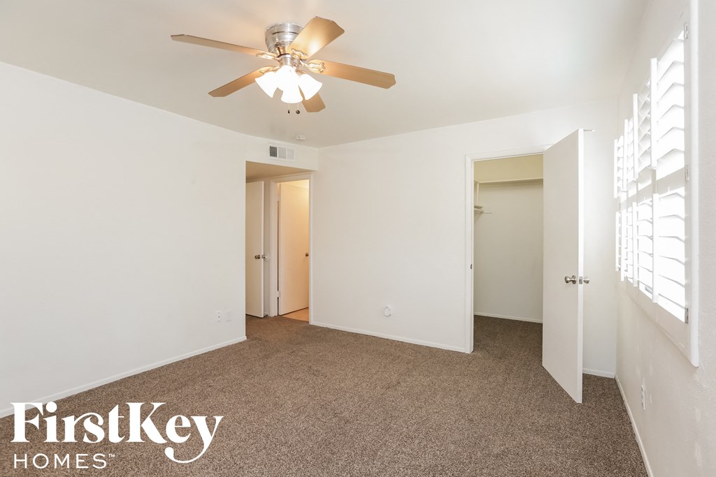 a bedroom with a ceiling fan and white walls