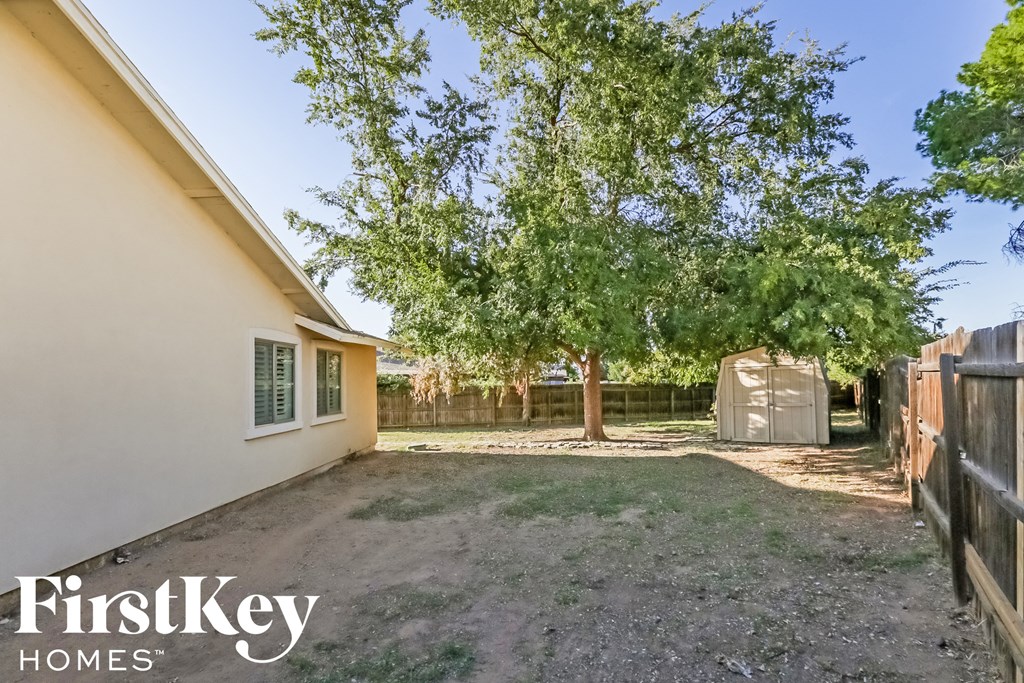 a backyard with trees and a fence and a house