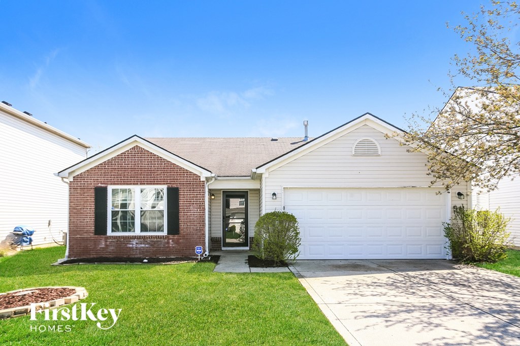 A house with a brick facade and a white garage door is for sale.