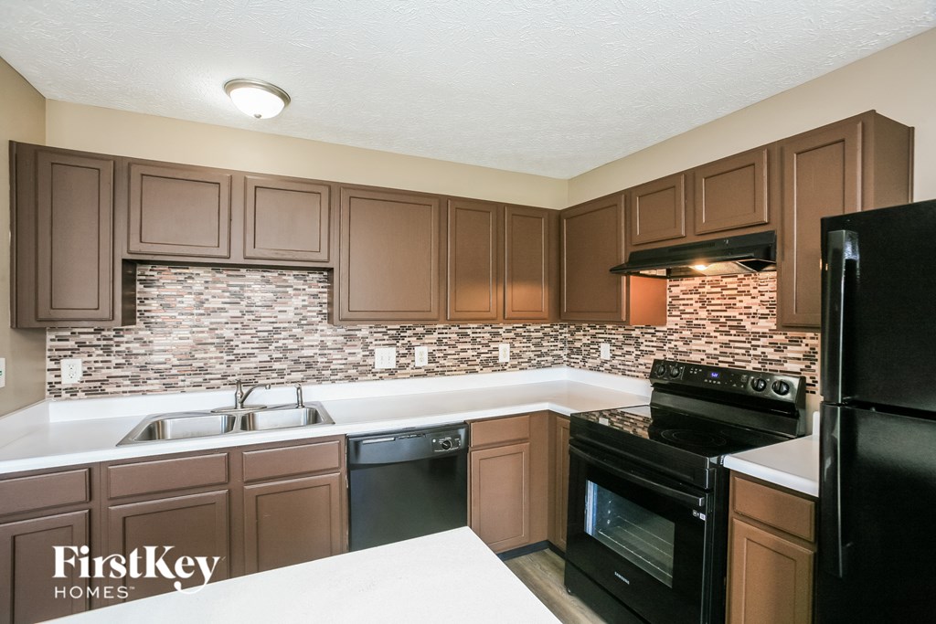 A kitchen with brown cabinets and black appliances.
