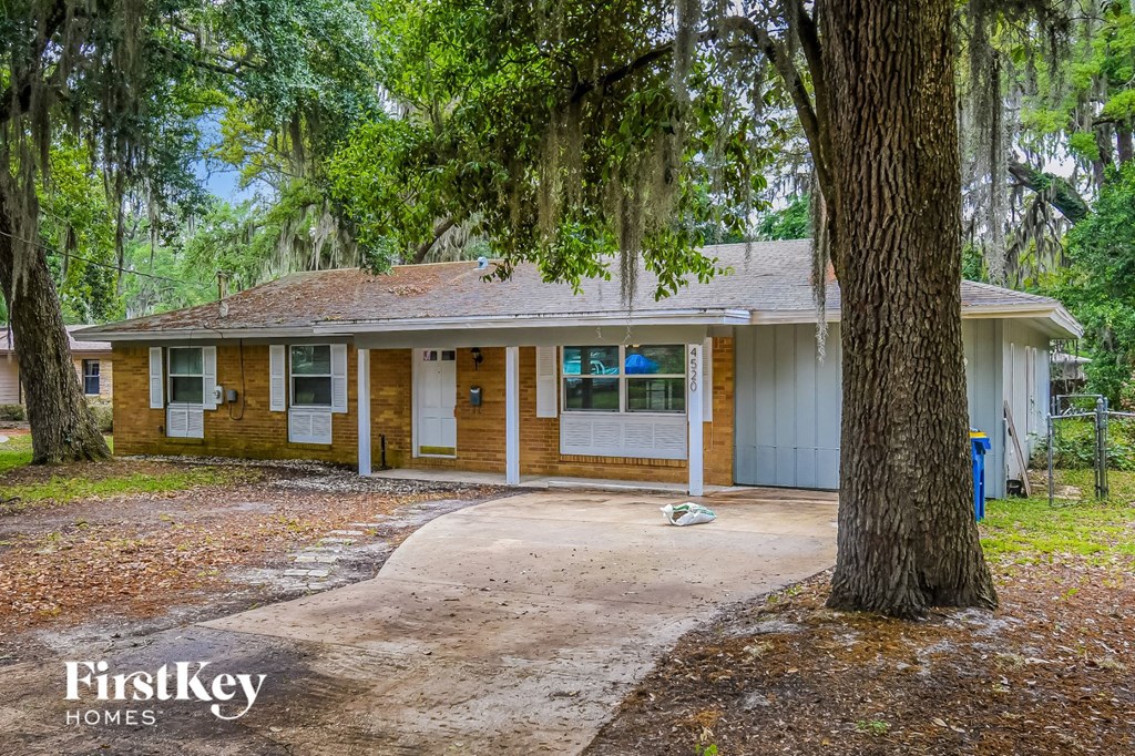 the front of a house with trees and a driveway